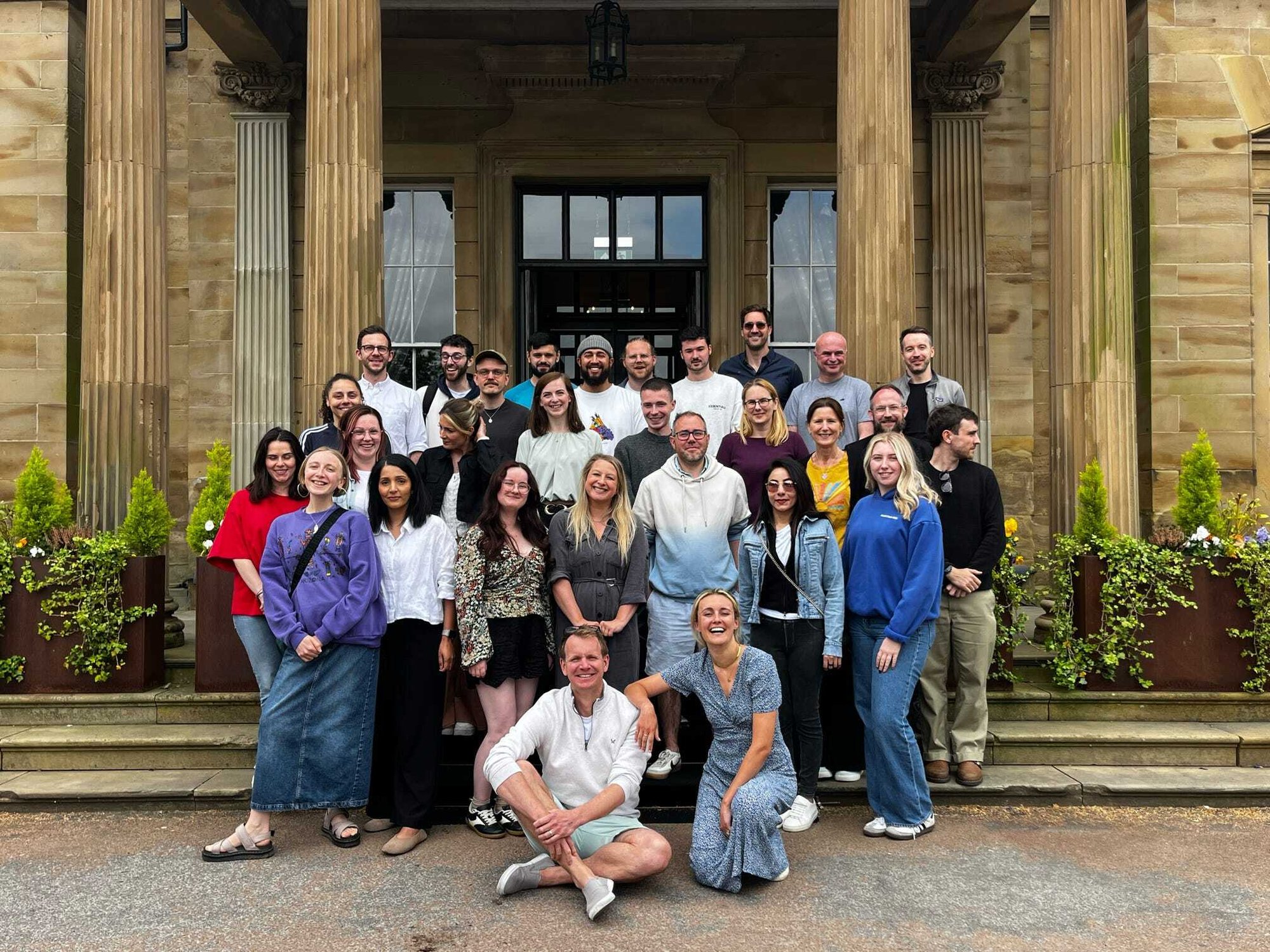 The Little Journey team are stood in a group outside, smiling for a picture The Little Journey team are stood in a group outside, smiling for a picture