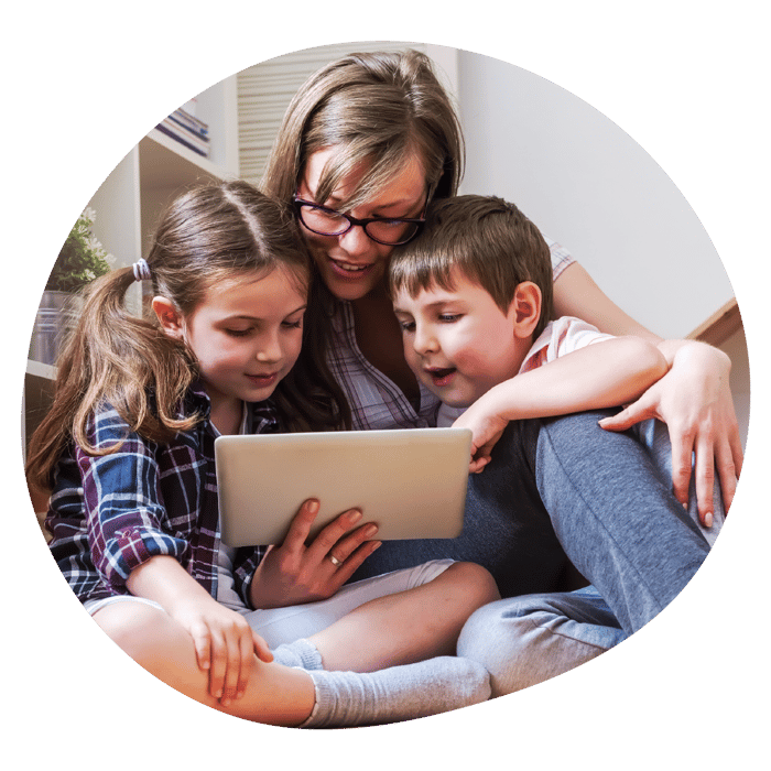 A parent and their two children are sat closely looking at a tablet.