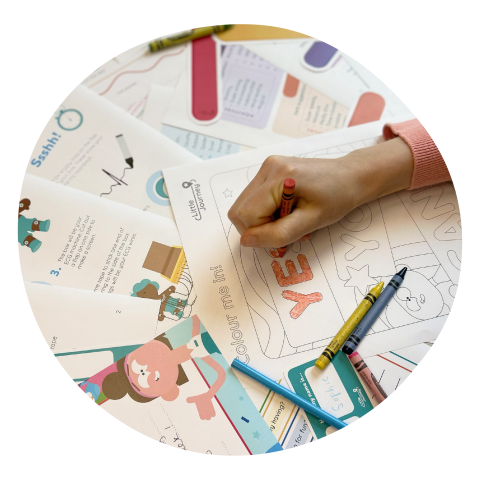 A person is colouring in, surrounded by activity sheets, crayons and pencils