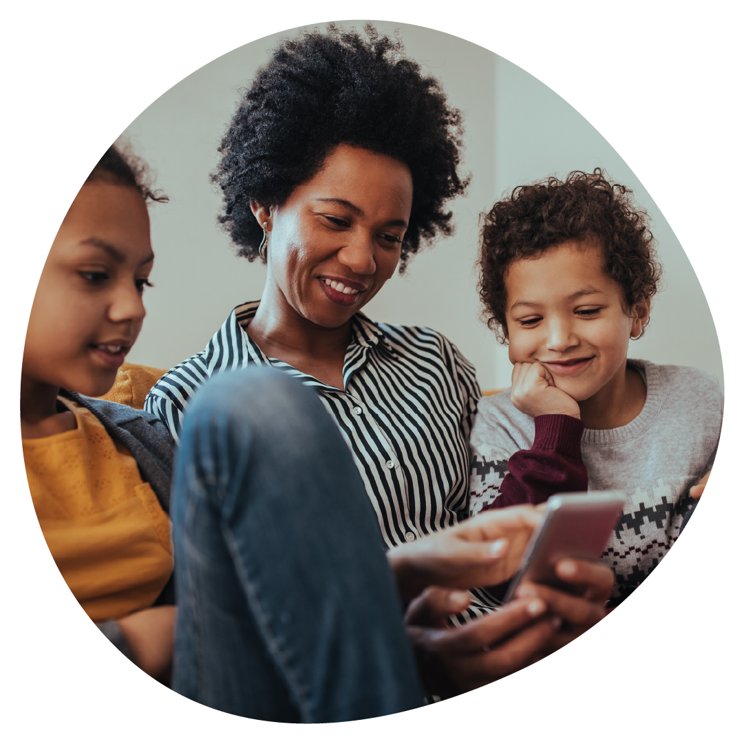 A parent and their two children are sat together smiling and looking at a mobile phone